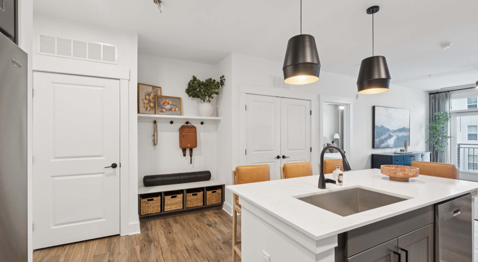 Modern apartment interior showcasing a sleek kitchen island, elegant pendant lights, and cozy seating area with natural light pouring in at The Rowley in Murfreesboro.