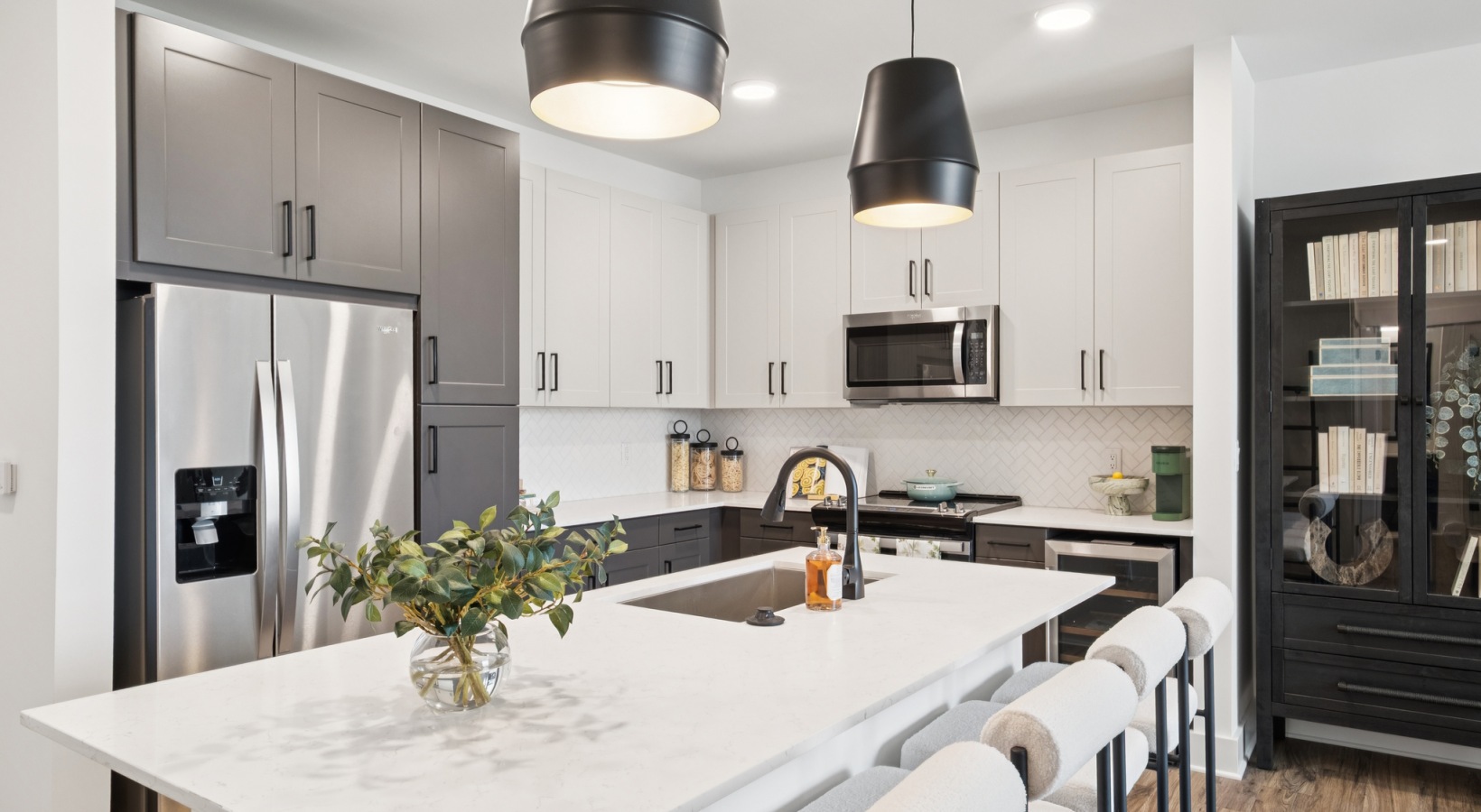 Modern kitchen with sleek white countertops, elegant two-tone cabinetry, stainless steel appliances, and stylish pendant lighting at your apartment in Murfreesboro