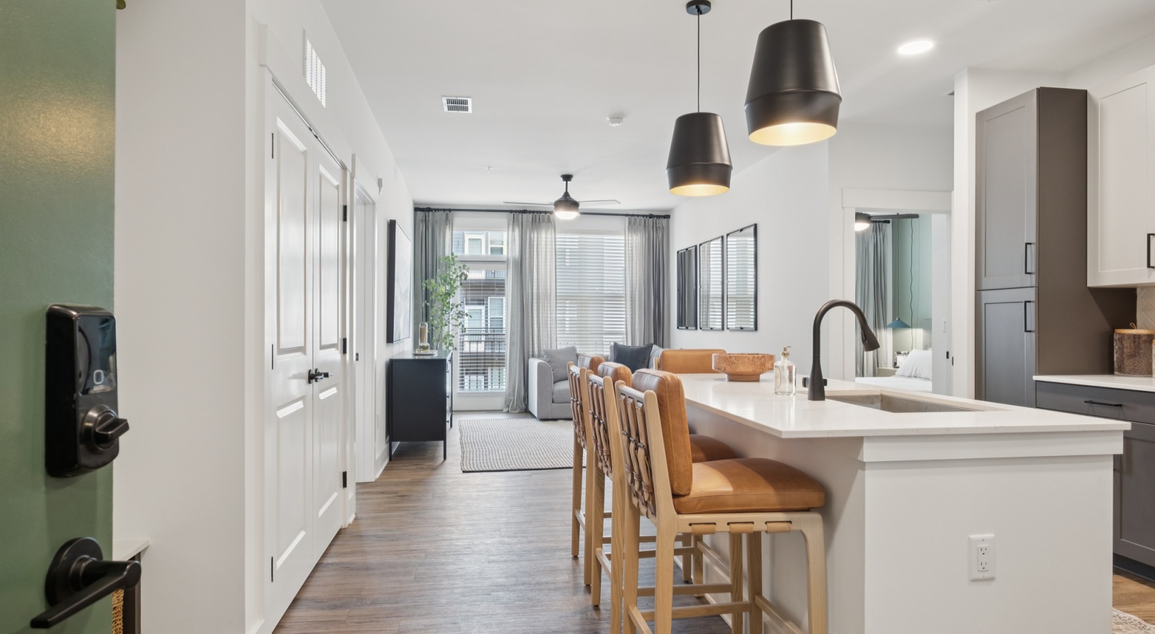 Modern open-concept apartment featuring a stylish kitchen with island seating, sleek lighting fixtures, and a cozy living area with natural light at your apartment at The Rowley in Murfreesboro.