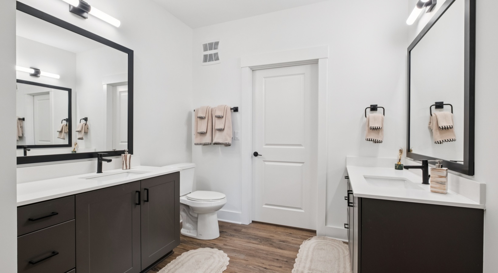 Elegant bathroom featuring dual vanities, modern black fixtures, and stylish wood flooring for a luxurious touch at The Rowley in Murfreesboro