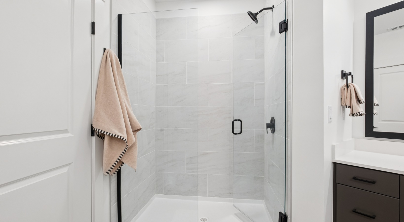 Elegant bathroom with a modern glass-enclosed shower, featuring chic tiling and a sleek vanity for a sophisticated touch at The Rowley in Murfreesboro.
